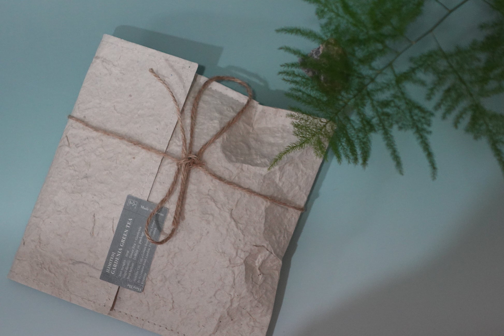 Package wrapped in brown paper with string on a light blue background