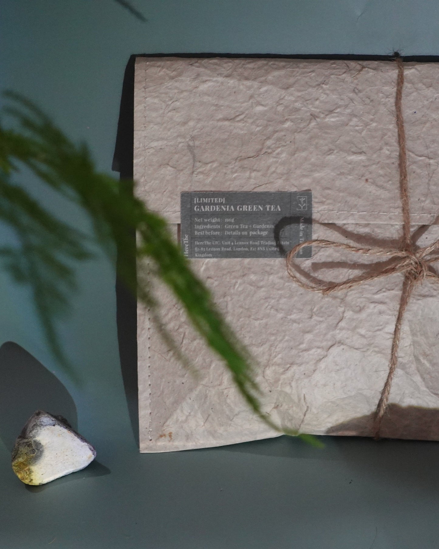 Product packaging with textured surface and twine bow on a gray background