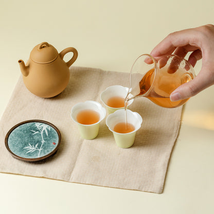 Tea-making scene with a teapot, cups, and a hand pouring tea.